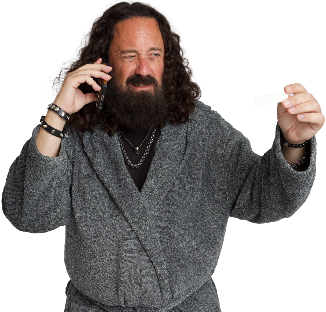 A man in a robe holding a positive COVID-19 test while on the phone.